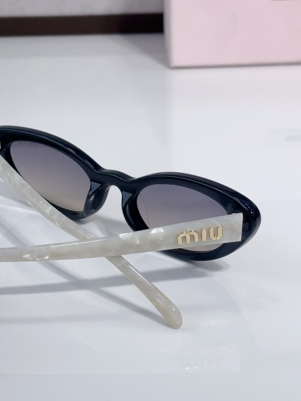 Close-up of cat-eye sunglasses with black frames and 'miu' logo on temple.