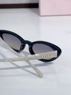 Close-up of cat-eye sunglasses with black frames and 'miu' logo on temple.