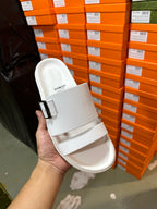 Hermes white slide sandal with buckle strap, held in hand