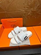 Hermes white slide sandals with two buckle-strap bands, side view