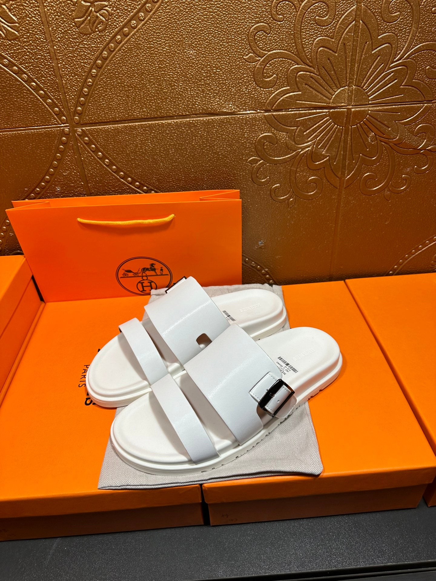 Hermes white slide sandals with two buckle-strap bands, side view