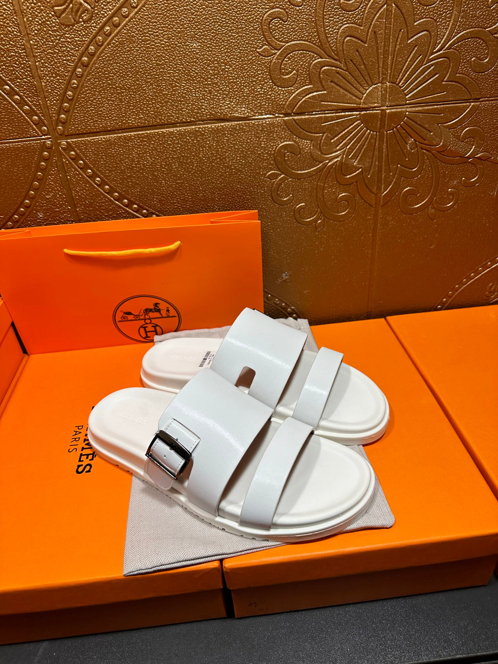 Hermes white slide sandals with wide straps and silver buckle closures