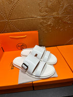 Hermes white slide sandals with wide straps and silver buckle closures