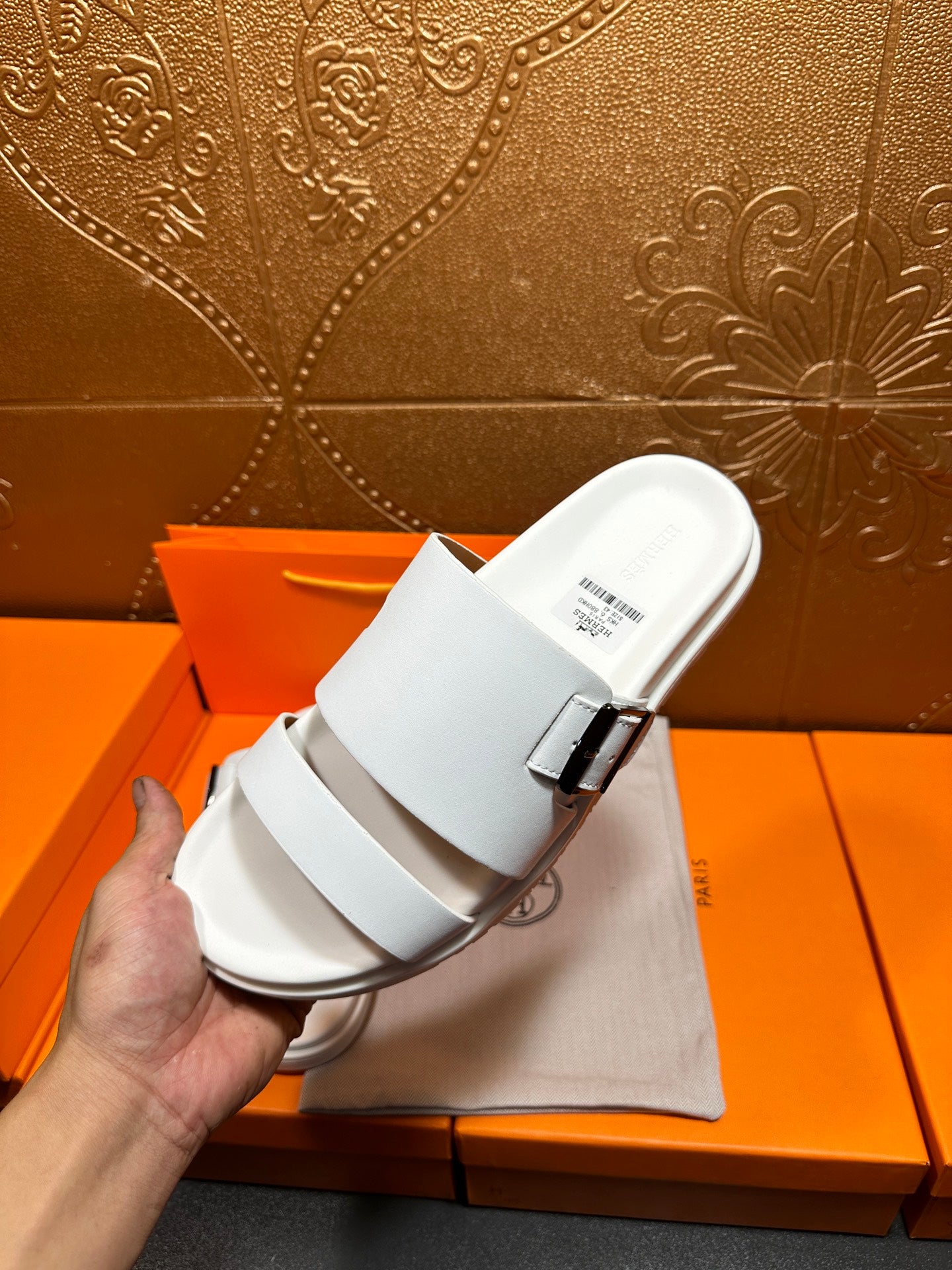 Hermes white slide sandal with adjustable buckle strap, close-up in hand