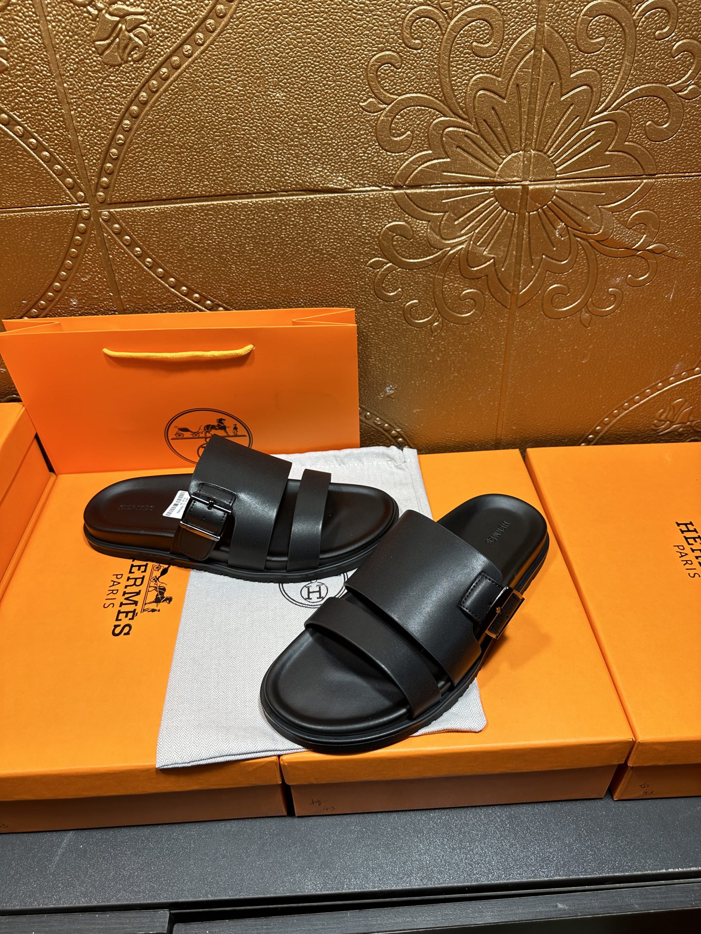 Black leather slide sandals with wide buckled straps, pair on dust bag and box