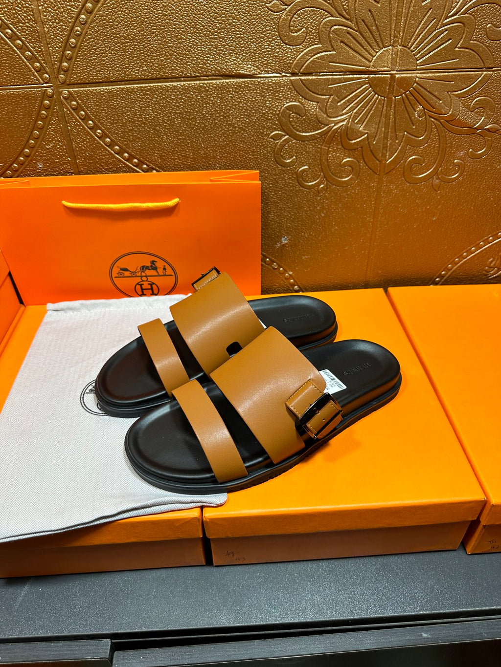 Tan and black Hermes slide sandals, side view with buckles and foot straps