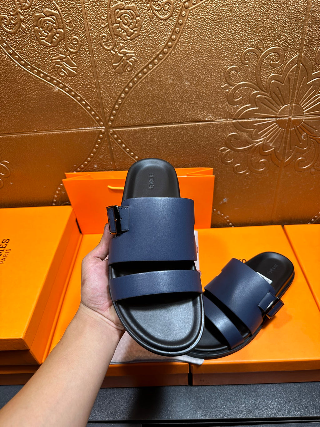 Hermes dark blue sandals from heel view with back strap and rubber sole.
