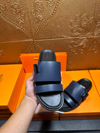 Hermes dark blue sandals from heel view with back strap and rubber sole.
