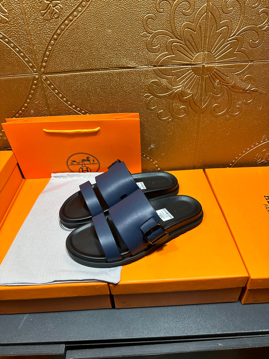 Hermes dark blue slide sandals with double straps and buckled leather detail.