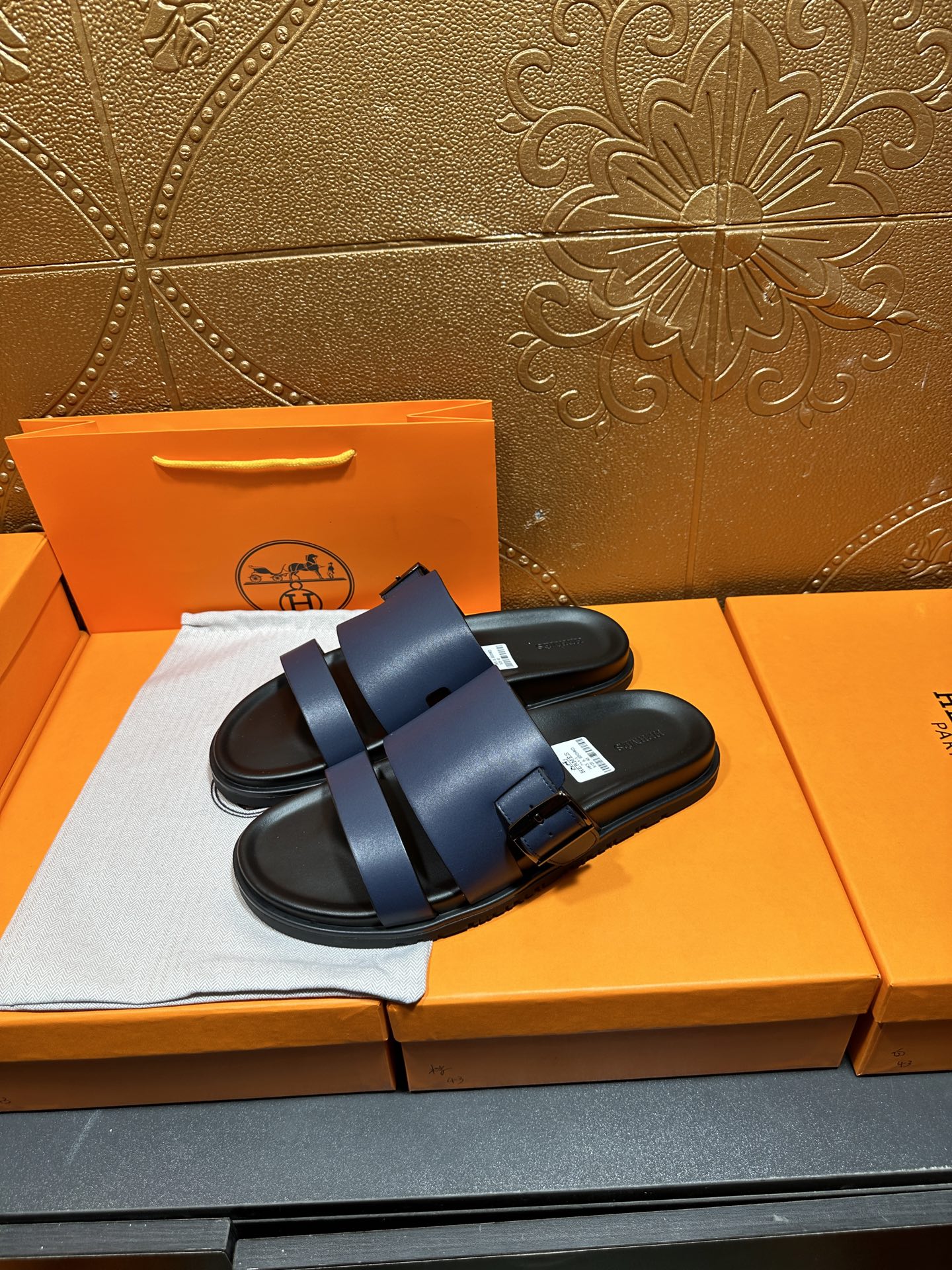 Hermes dark blue slide sandals with double straps and buckled leather detail.