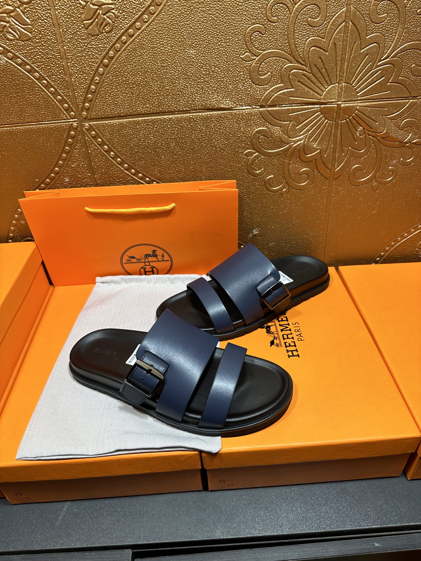 Hermes dark blue sandals with adjustable buckle straps and black rubber sole.