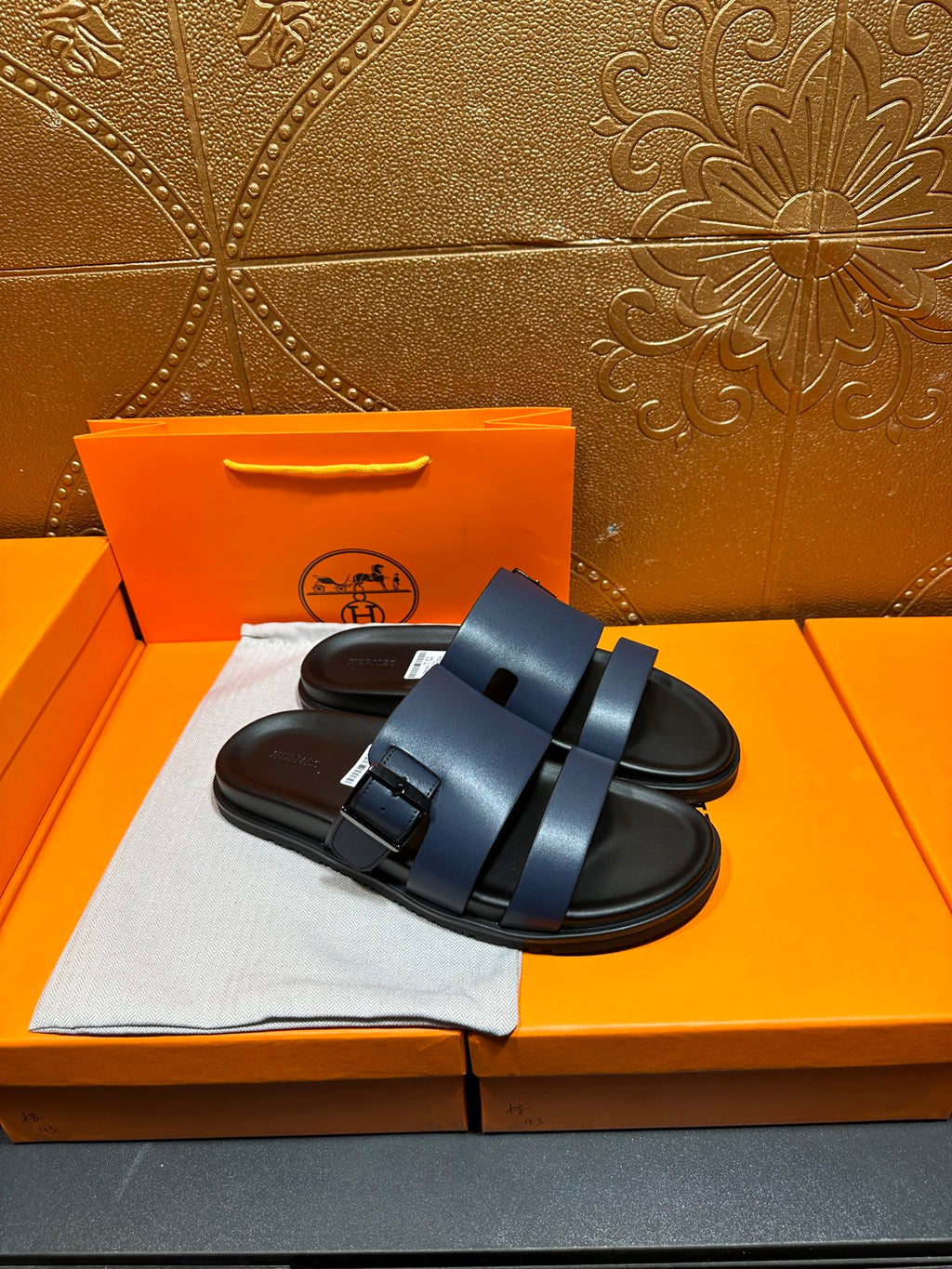 Hermes dark blue sandals with two wide straps and textured footbed, side view.