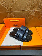 Hermes dark blue sandals with two wide straps and textured footbed, side view.