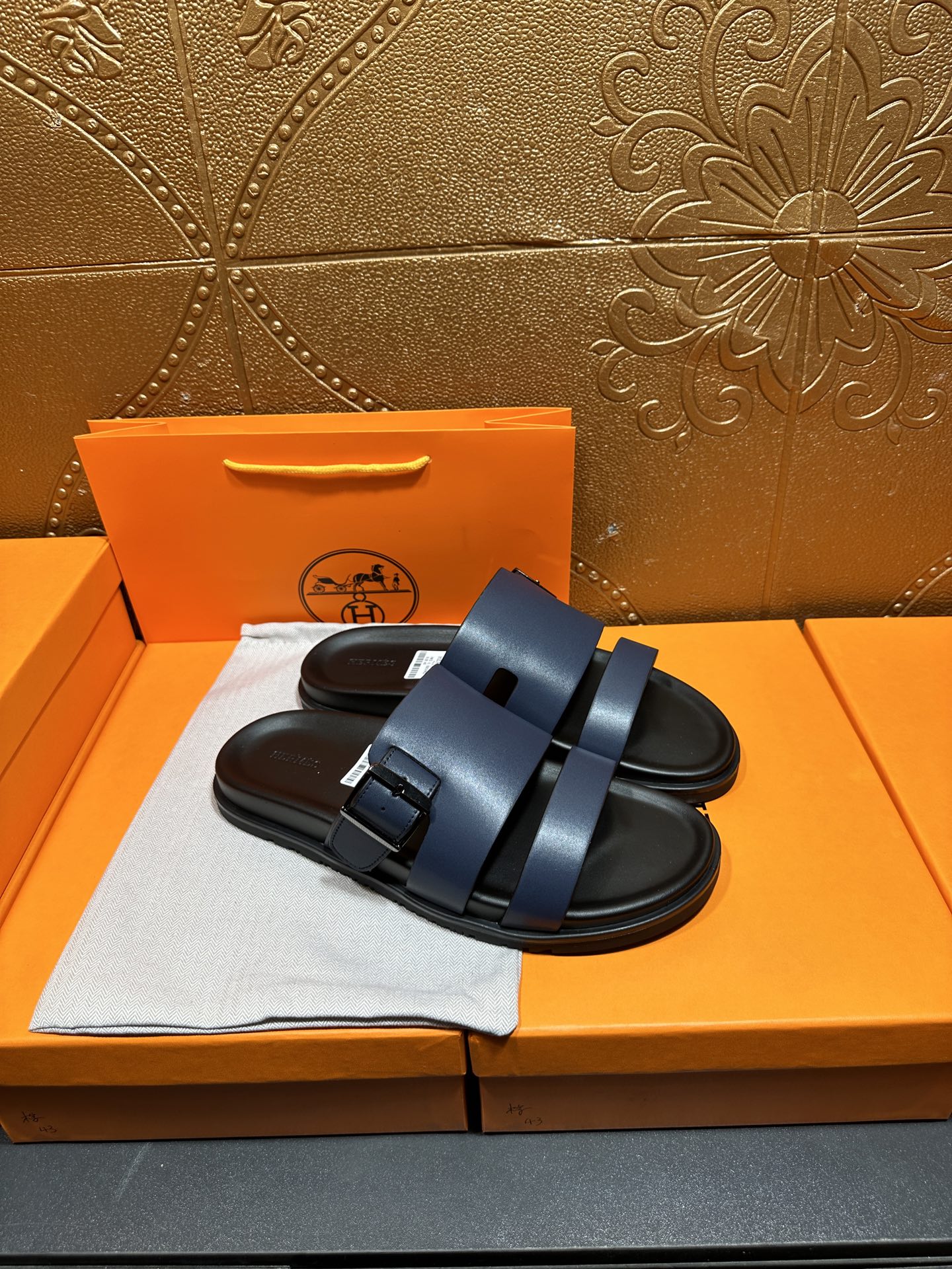 Hermes dark blue sandals with two wide straps and textured footbed, side view.