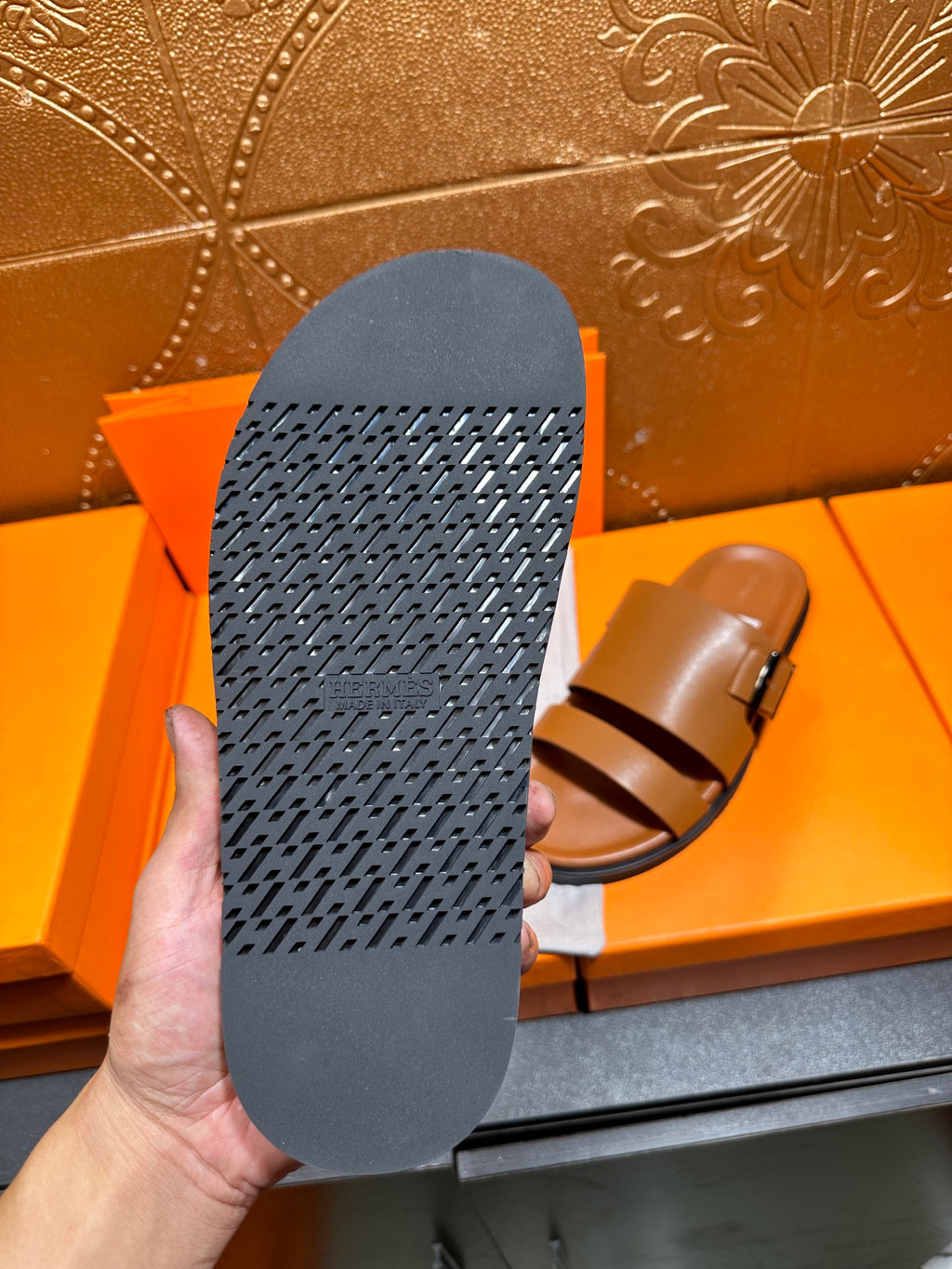 Tan slide sandal outsole with textured dark rubber tread, viewed from bottom