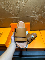 Tan leather slide sandals held up, two buckle straps and cushioned sole
