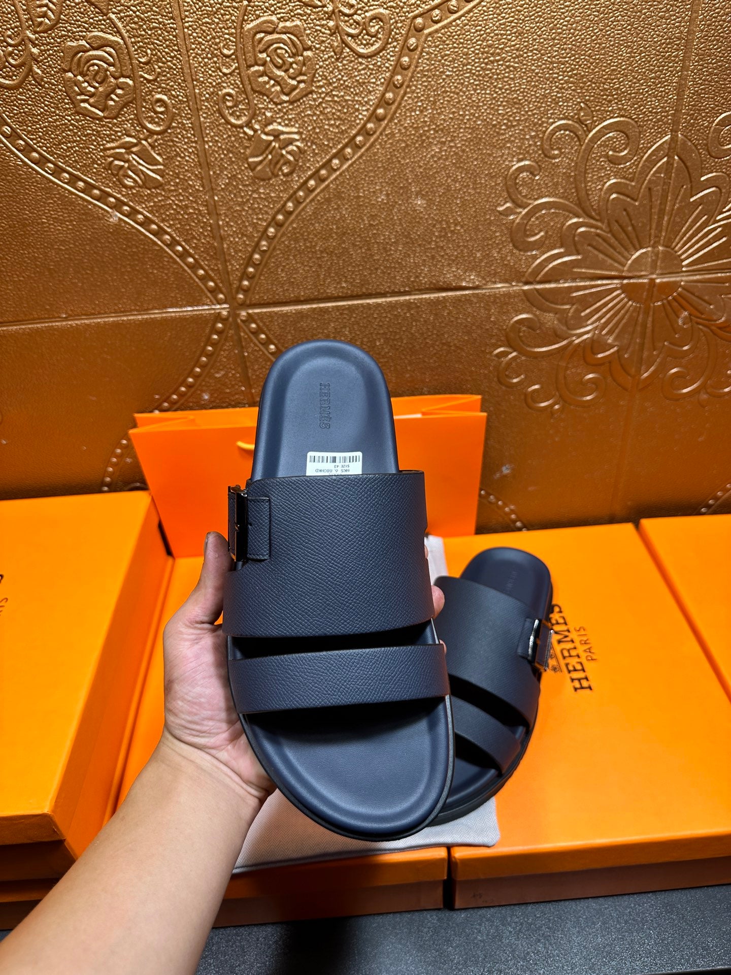 Blue slide sandals with two buckled straps, held upright in hand
