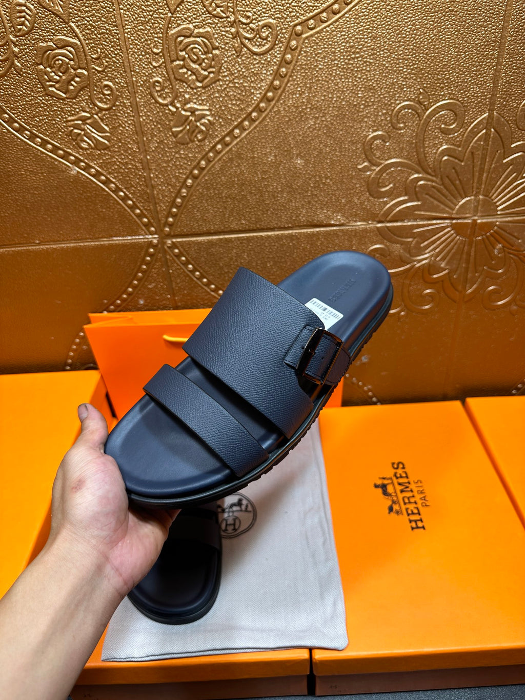 Blue slide sandals with two buckled straps, held in hand for close-up