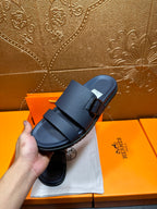 Blue slide sandals with two buckled straps, held in hand for close-up
