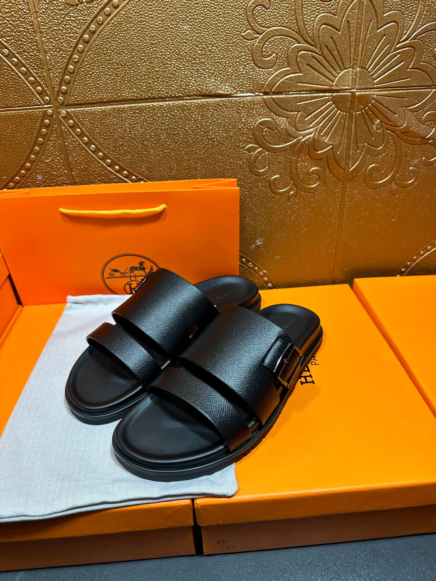 Hermes black leather slide sandals, two-strap design, displayed on shoebox