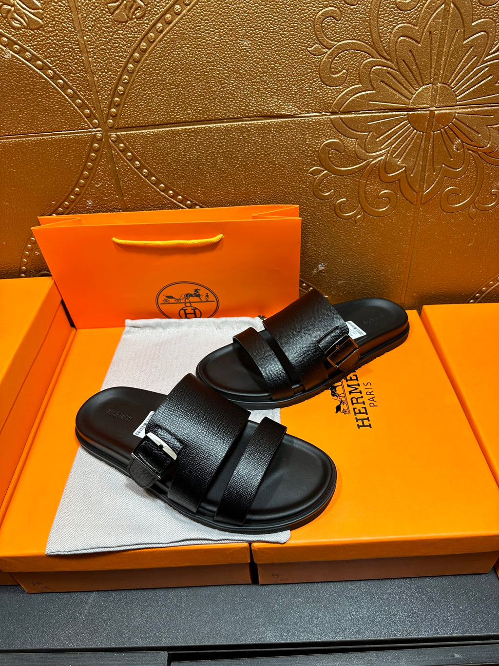 Hermes black slide sandals with double straps, side view on shoebox