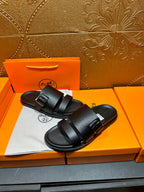 Hermes black leather slide sandals with two straps, angled view on shoebox