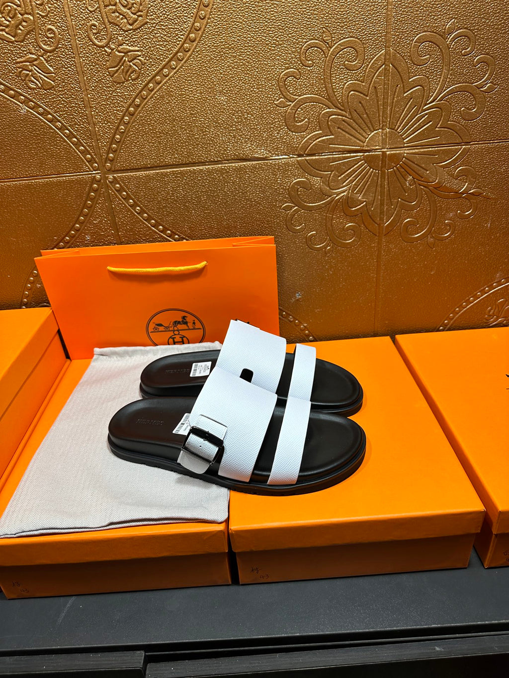 White slide sandals with double strap across instep and black outsole
