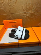 White slide sandals with double strap across instep and black outsole