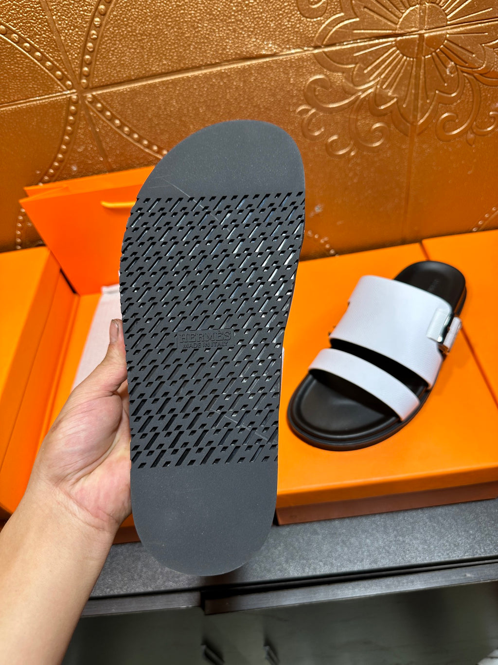Slide sandal outsole underside with textured rubber tread, held in hand