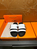 Hermes slide sandals with white straps and black cushioned footbed