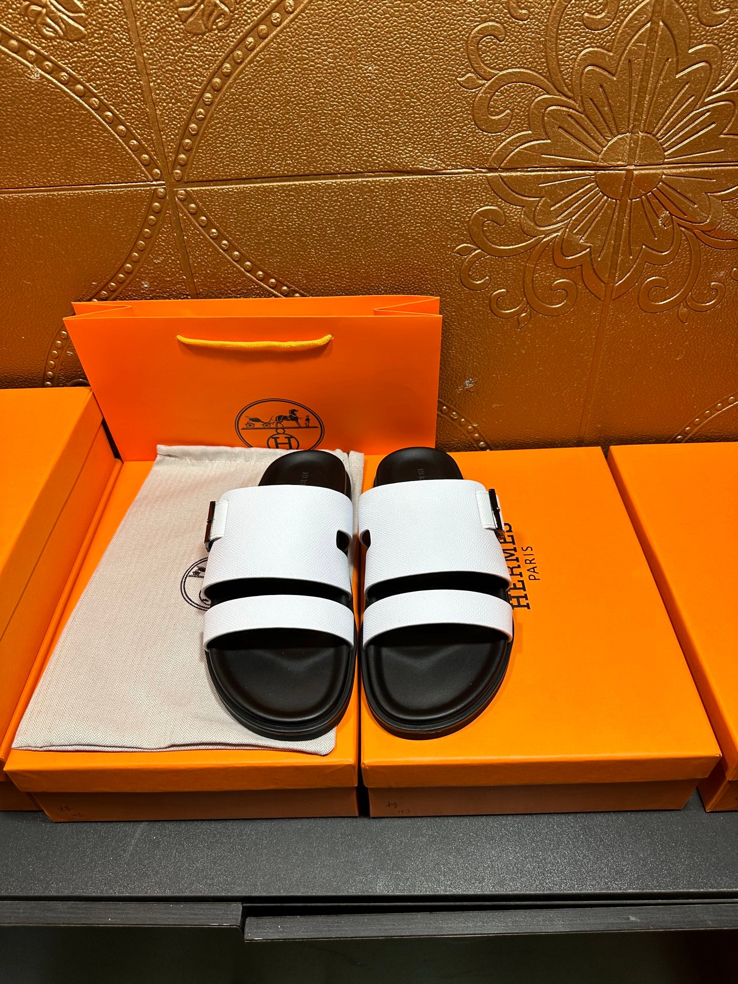 Hermes slide sandals with white straps and black cushioned footbed