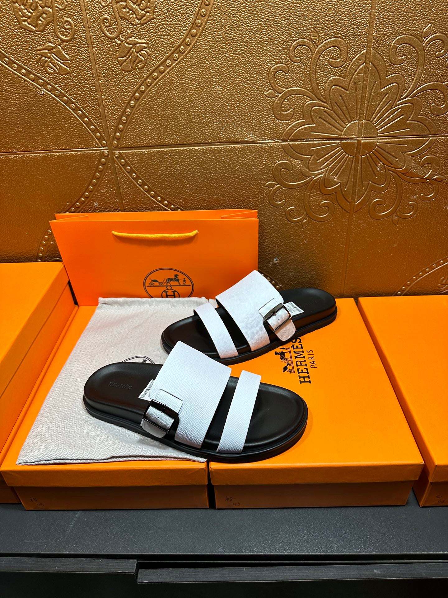 Pair of white-and-black slide sandals with adjustable buckle straps