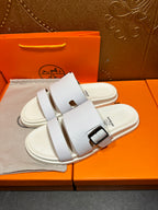 Hermes white leather slide sandals with two straps and silver buckle, angled view