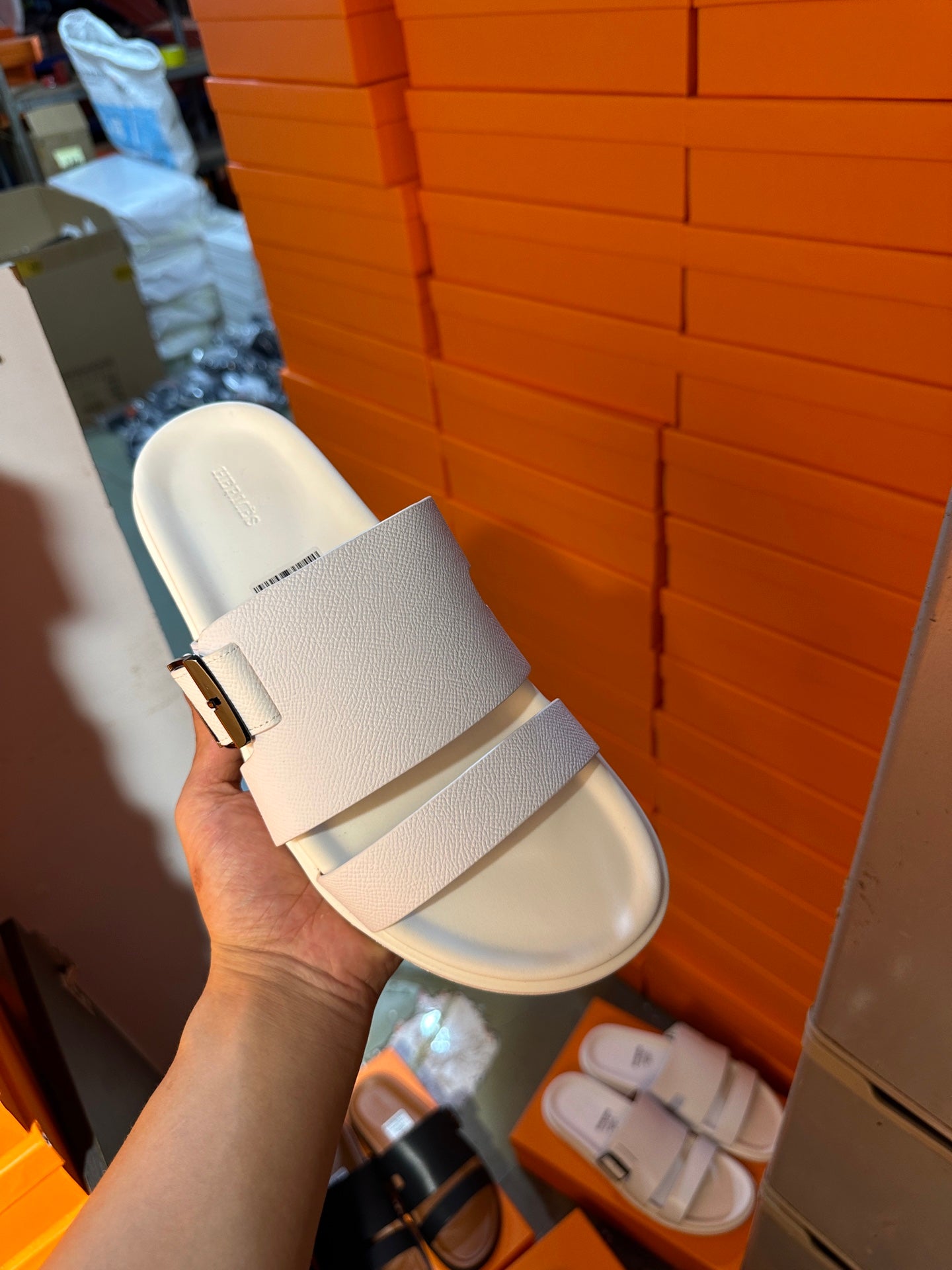 Hermes white leather slide sandals held in hand, single sandal with silver buckle