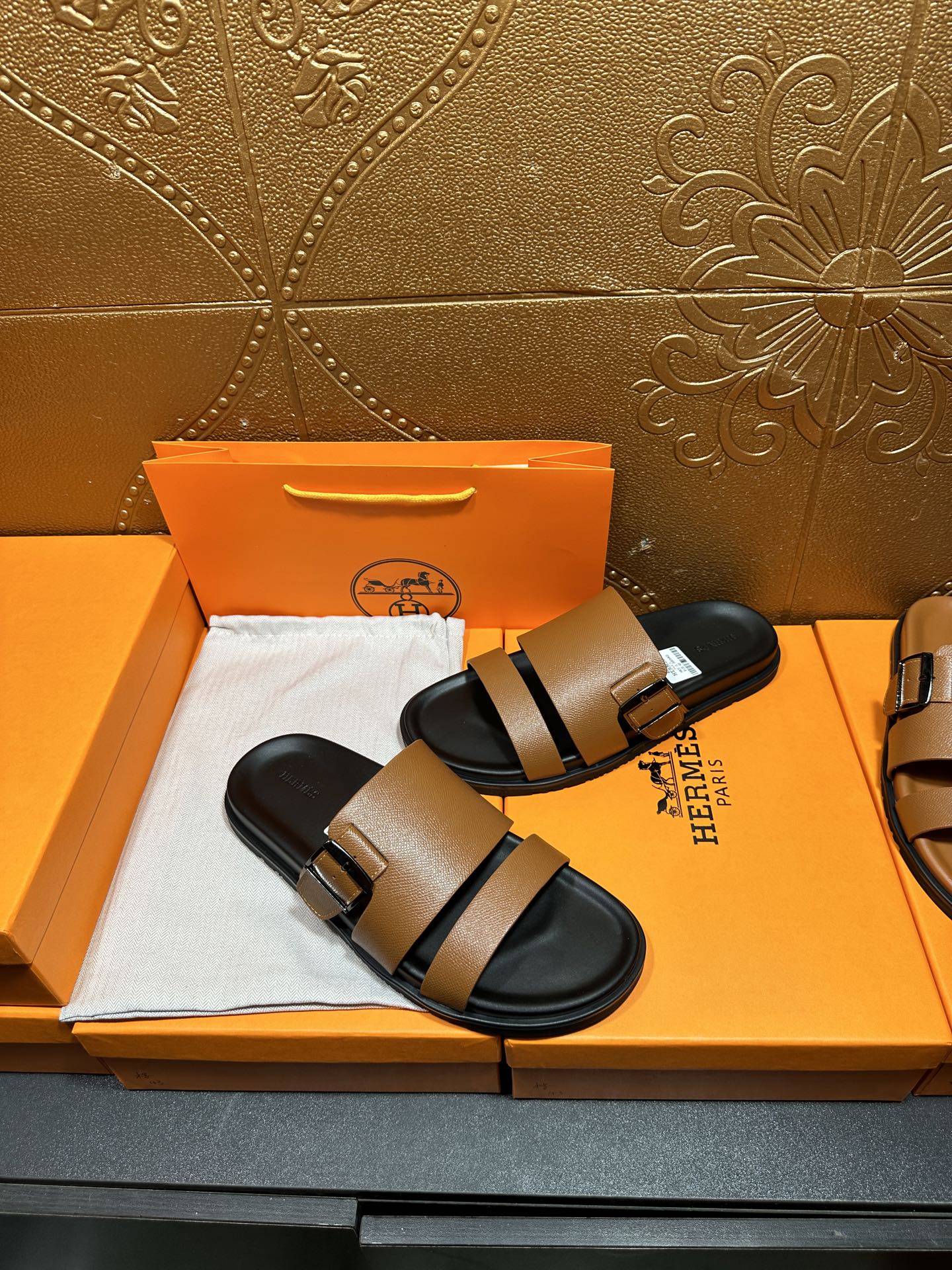 Brown slide sandals with black double strap bands and silver-tone buckles, black footbed.