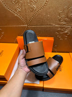 Brown slide sandal with black strap and silver-tone buckle held in hand.