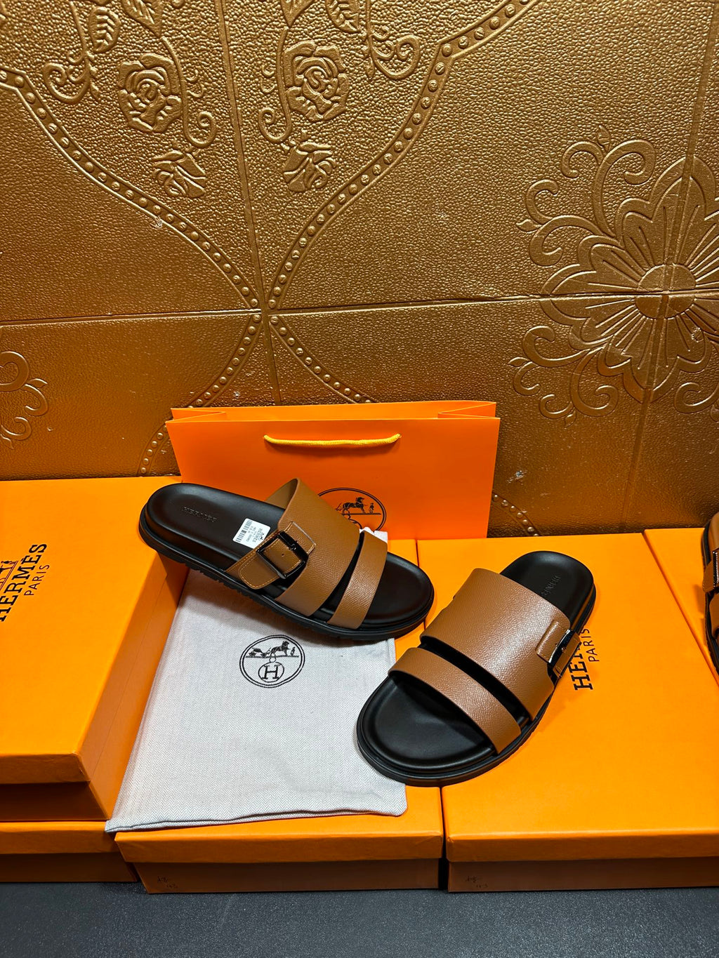 Brown slide sandals with black strap and silver-tone buckle, shown on black footbed.