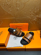 Brown slide sandals with black strap and silver-tone buckle, shown on black footbed.