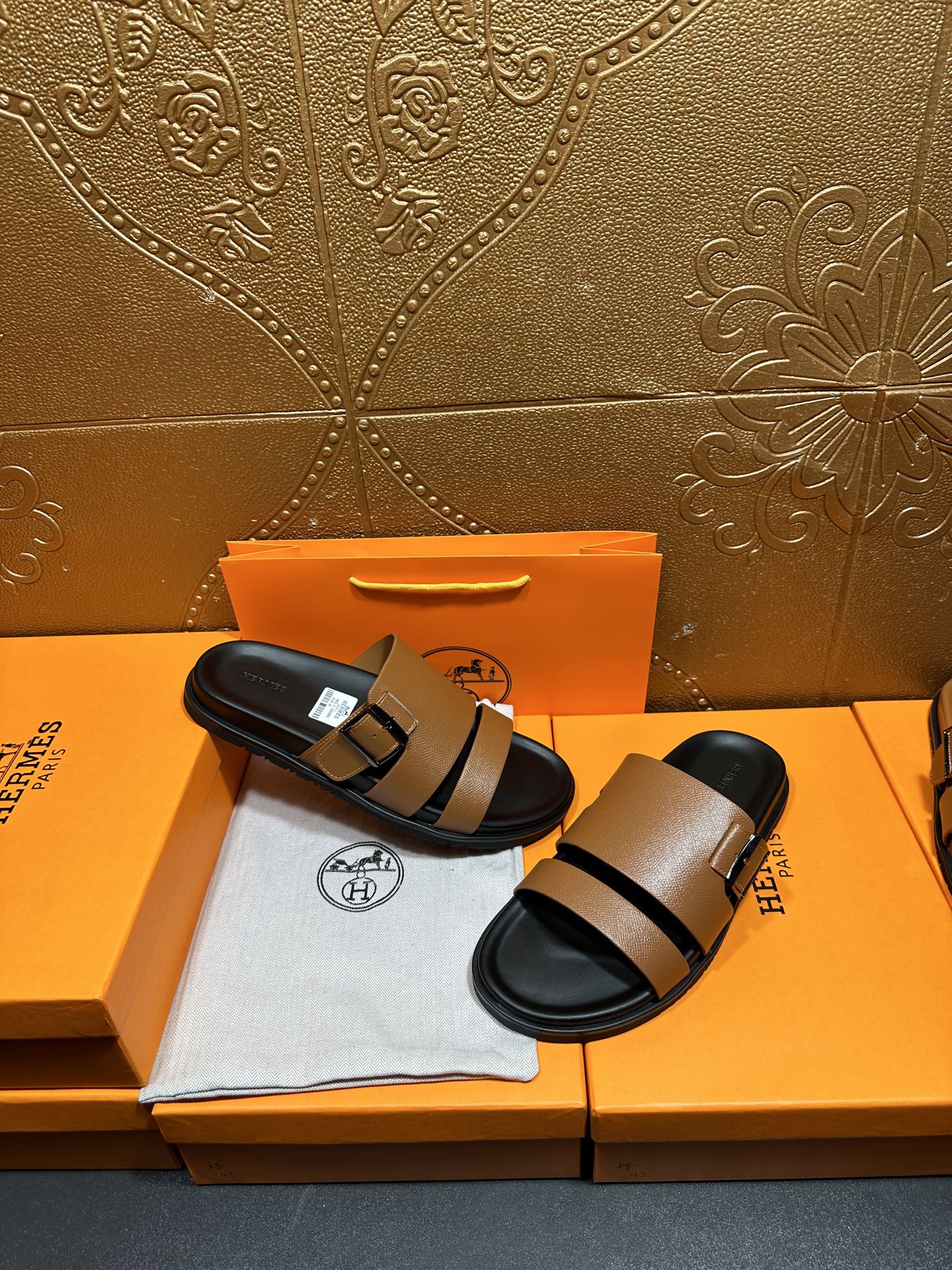 Brown slide sandals with black strap and silver-tone buckle, shown on black footbed.