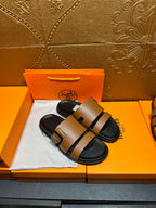 Tan-brown slide sandals with black strap and metal buckle, black sole.