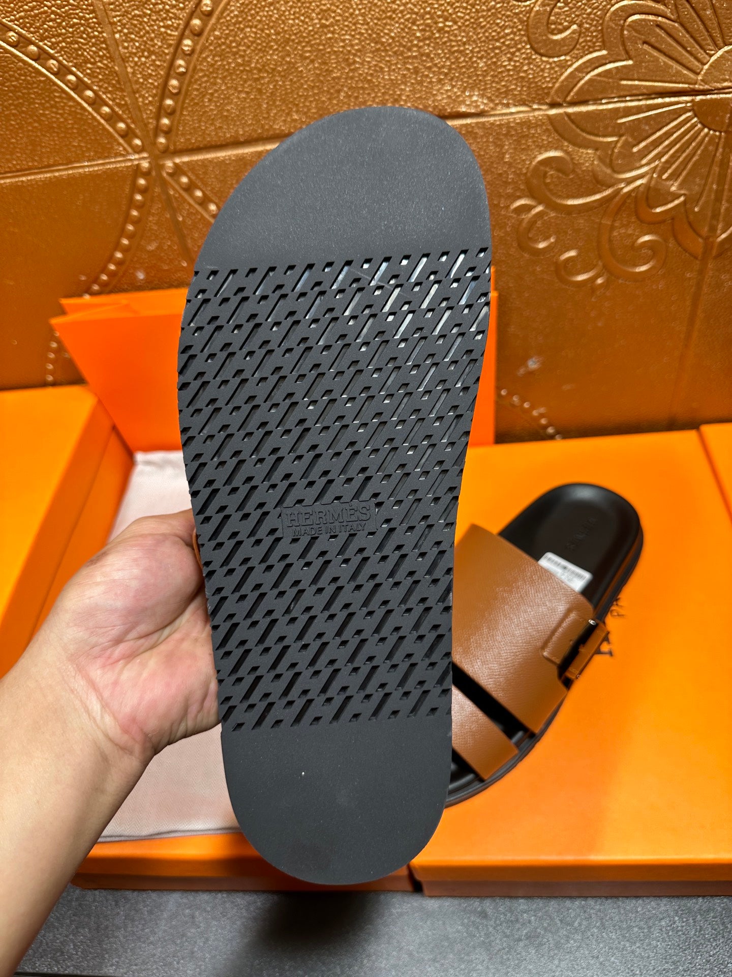 Black sandal outsole with textured tread pattern, underside of brown slide sandal.