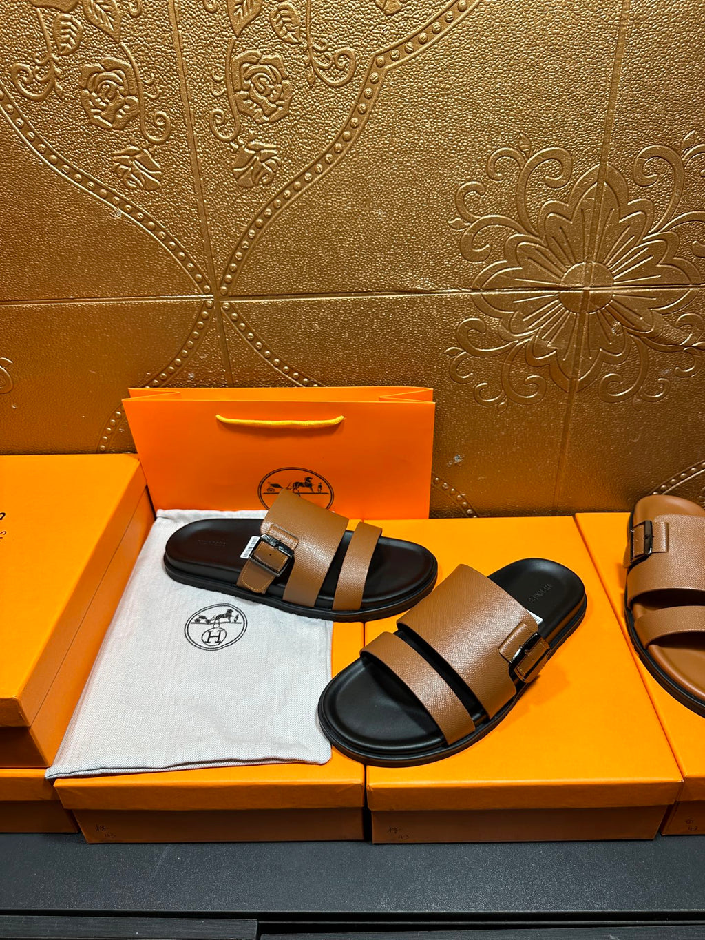 Brown leather slide sandals with black double straps and silver-tone buckles, black sole.