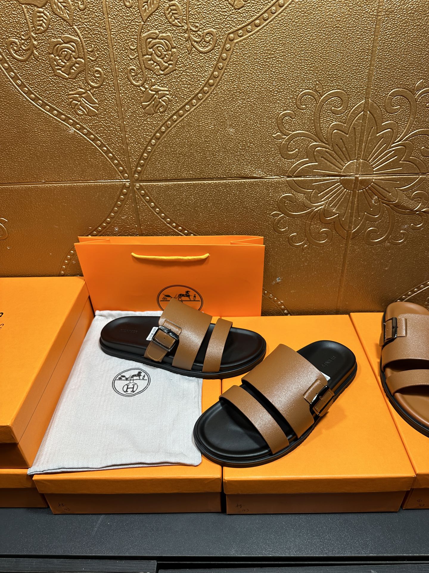 Brown leather slide sandals with black double straps and silver-tone buckles, black sole.