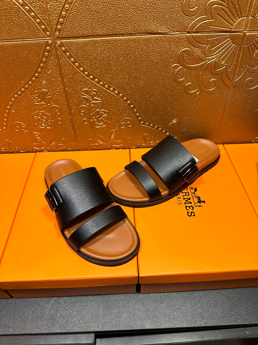 Black slide sandals with two wide straps and tan footbeds, side-by-side view