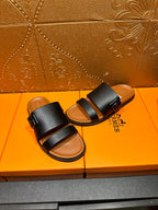 Black slide sandals with two wide straps and tan footbeds, side-by-side view