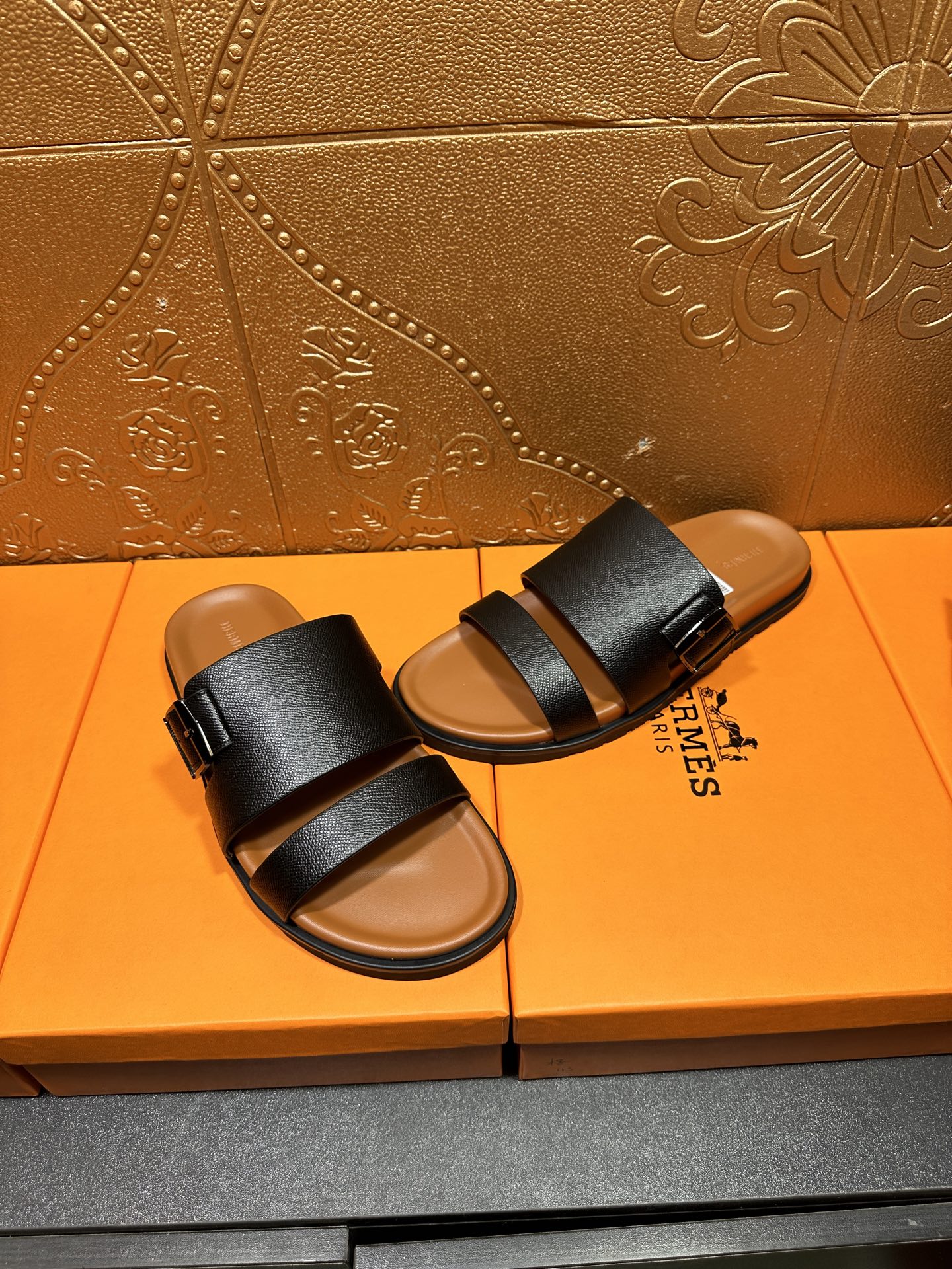 Black slide sandals with two wide straps and tan footbeds, side-by-side view
