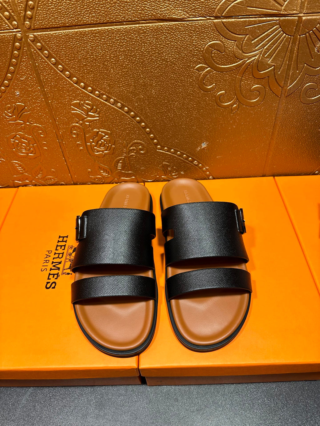 Black slide sandals with two wide straps and tan footbed, side view