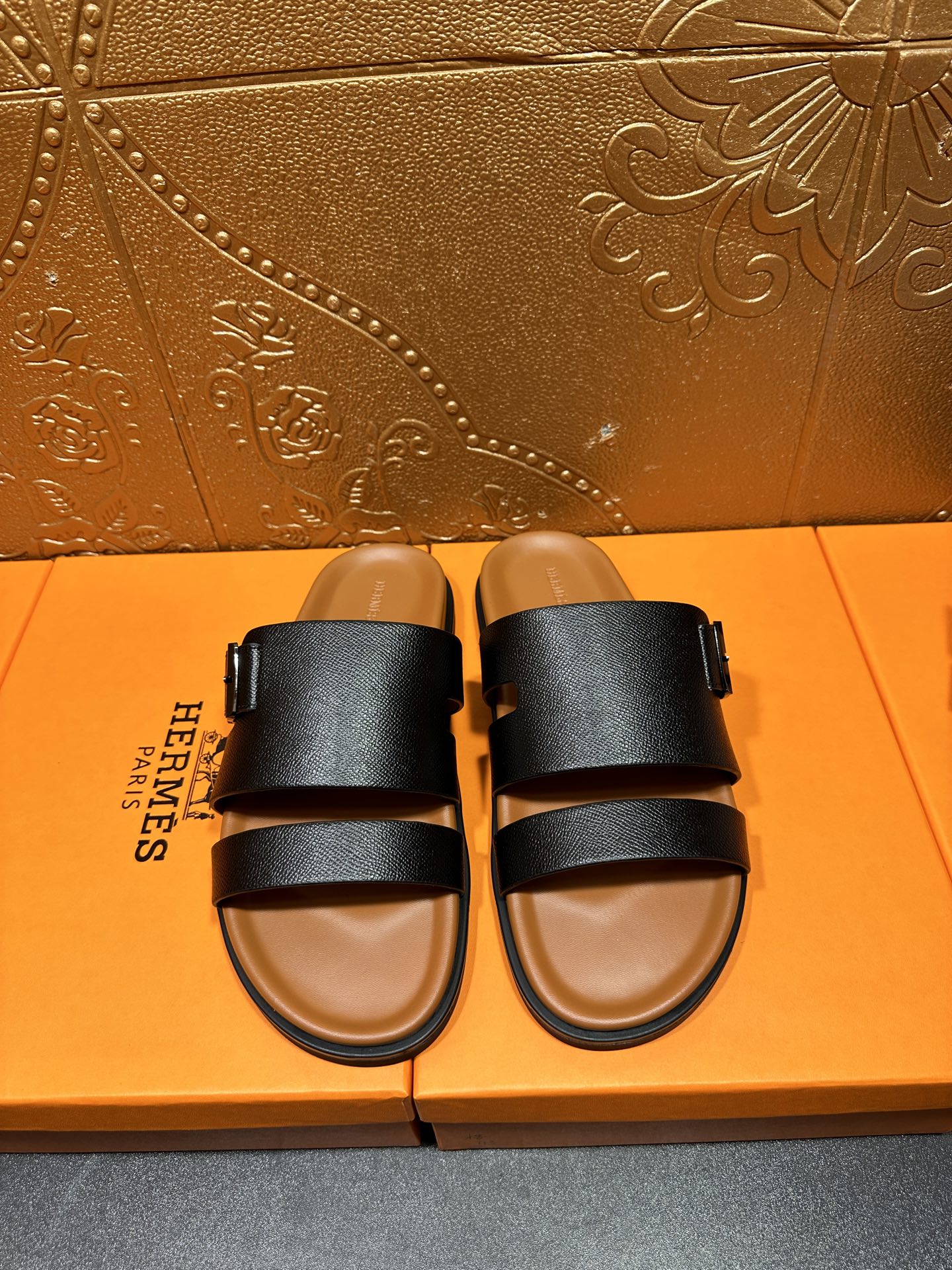 Black slide sandals with two wide straps and tan footbed, side view