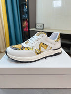 White sneakers with gold baroque-style print, lace-up front, and thick rubber sole