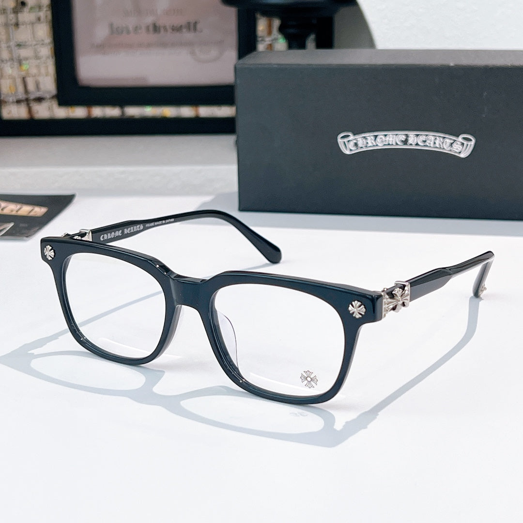 Chrome eyeglasses with dark frames, gold-toned cross detail at the hinge, clear lenses